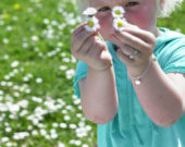 Girl in meadow holding daisies