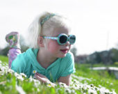 Girl with sunglasses in meadow of daisies