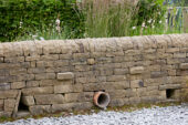 Stenen muur met doorgang voor egels, egel snelweg 