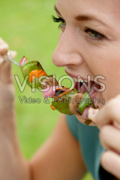 Lady eating vegetable skewer