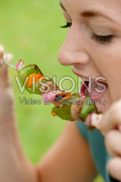 Lady eating vegetable skewer