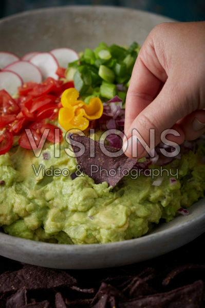 Dipping chip into garnished guacamole