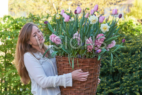 Young lady carrying basket with spring flowers
