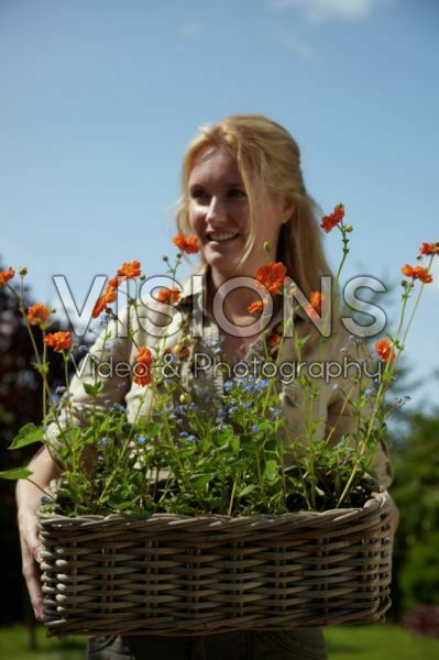 Woman holding basket with Geum and Myosotis